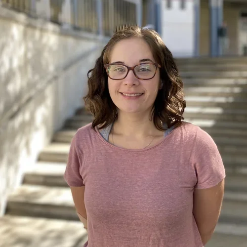 Headshot: a person smiling in front of stairs
