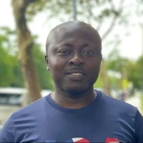 Headshot: a person smiling in front of trees