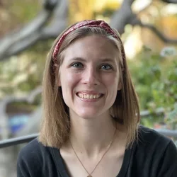 Headshot: a person smiling in front of a tree