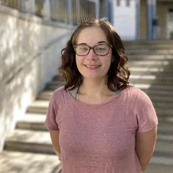Headshot: a person smiling in front of stairs